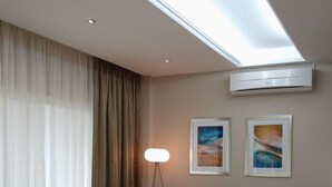 Una habitación de hotel moderna con un sofá, dos sillones, una lámpara de pie y una obra de arte en la pared.