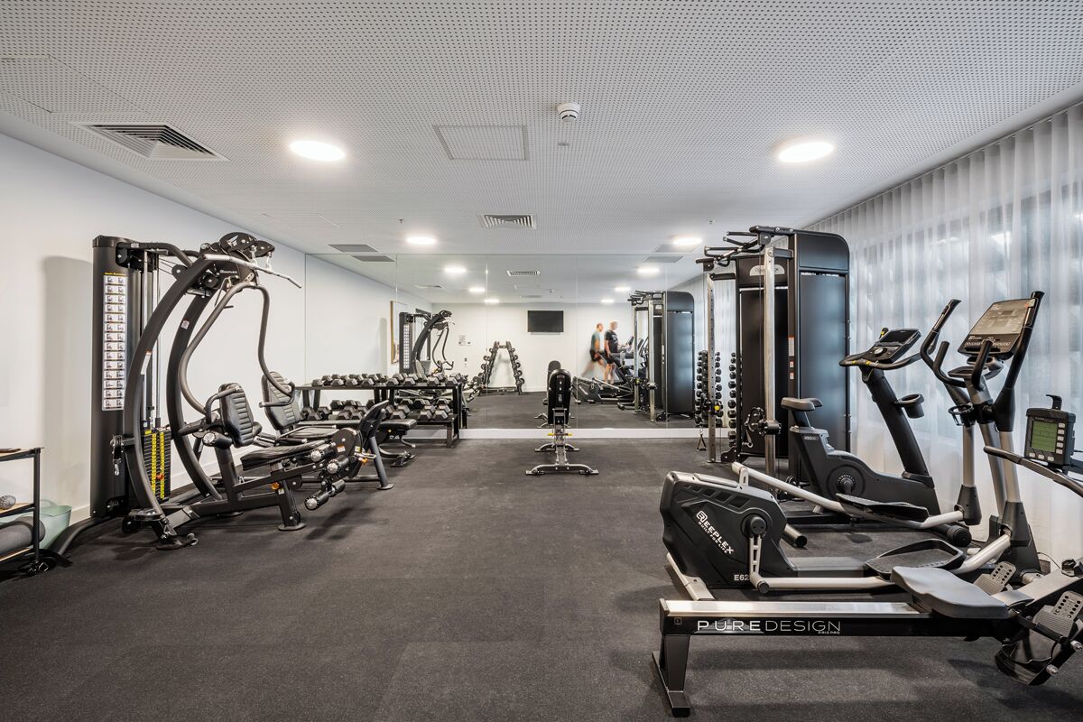 Una palestra con diverse attrezzature per l'esercizio fisico, tra cui tapis roulant, macchinari per pesi e pesi liberi.