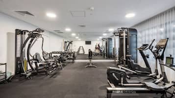 Una palestra con diverse attrezzature per l'esercizio fisico, tra cui tapis roulant, macchinari per pesi e pesi liberi.