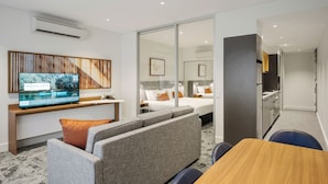 Une chambre d’hôtel moderne équipée d’une télévision, d’un canapé, d’une table à manger et d’un lit avec vue.