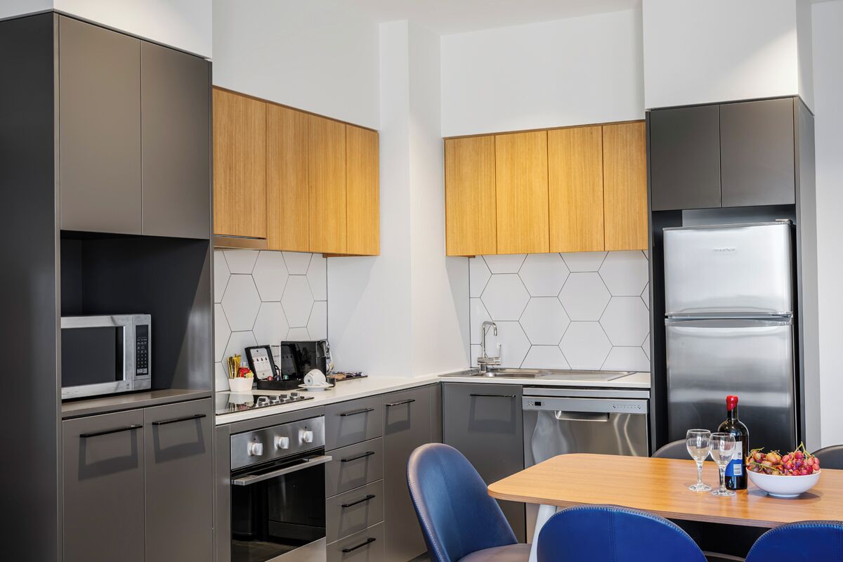Una cocina moderna con microondas, estufa y refrigerador, una mesa de comedor con sillas y un salpicadero de azulejos hexagonales.