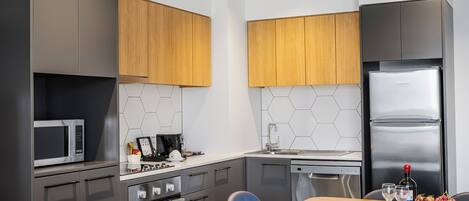 Une cuisine moderne équipée d’un four à micro-ondes, d’une cuisinière et d’un réfrigérateur, ainsi que d’une table à manger avec des chaises et d’un dosseret de crédence en carreaux hexagonaux.