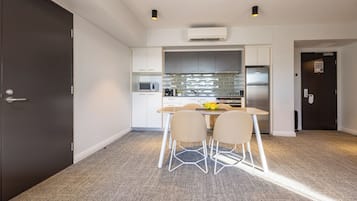 A compact kitchen with white cabinets, a microwave, a refrigerator, and a dining area with a table and chairs.