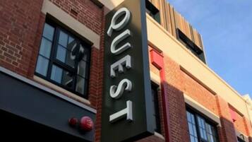 A building with a sign that reads "QUEST" on a vertical banner.