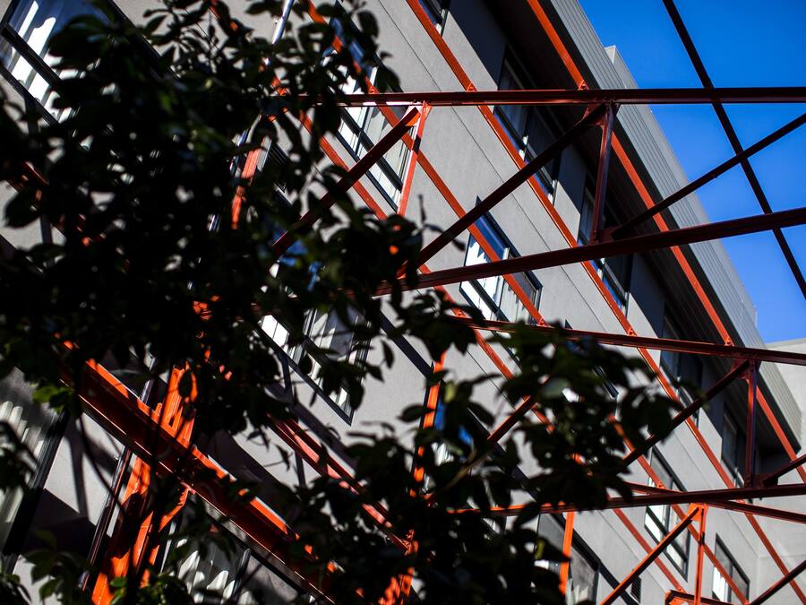 Un edificio moderno con fachada geométrica y elementos estructurales rojos.