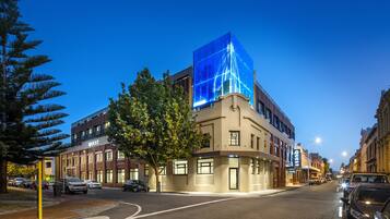 A modern building with a prominent blue glass facade, a brick base, and a sign labeled "QUEST".