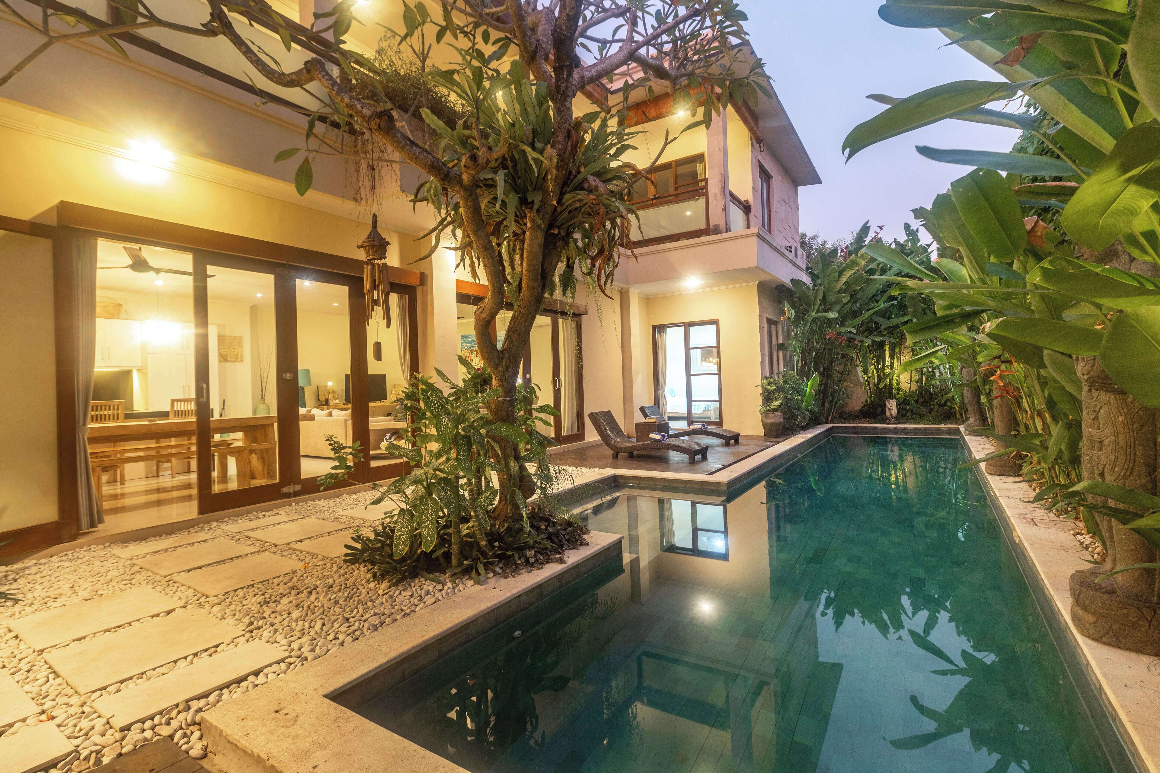Une maison moderne dotée d’une piscine, de grandes fenêtres et d’un jardin bien entretenu.