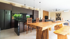 Una cocina moderna con armarios oscuros, una gran mesa de comedor de madera y una isla integrada.