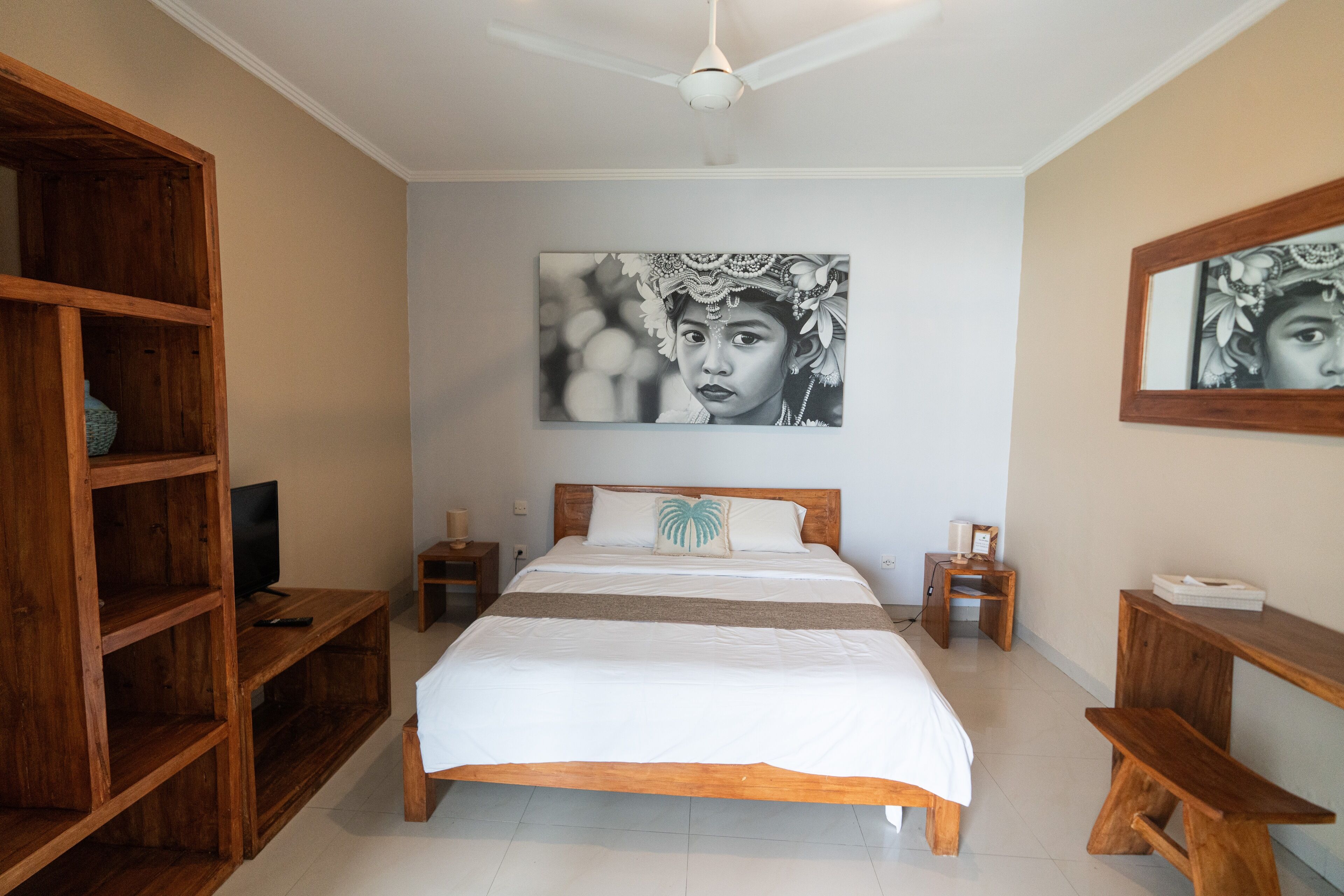 Une chambre à coucher avec un lit en bois, un téléviseur posé sur un meuble en bois et un grand tableau encadré accroché au mur.