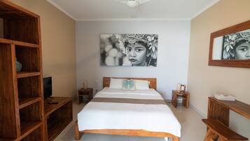 Une chambre à coucher avec un lit en bois, un téléviseur posé sur un meuble en bois et un grand tableau encadré accroché au mur.