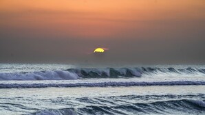 Un atardecer sobre el océano con olas rompiendo en la orilla.