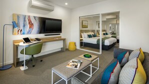 A modern hotel room with a desk, chair, and a bed with a large mirror. - Quest Griffith (Griffith)