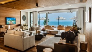 Amplia sala de estar con un ventanal grande con vistas al mar, amoblada con sofás, una mesa de centro y elementos decorativos.