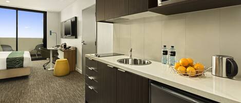 A modern kitchen with a sink, microwave, and a fruit bowl on the counter.