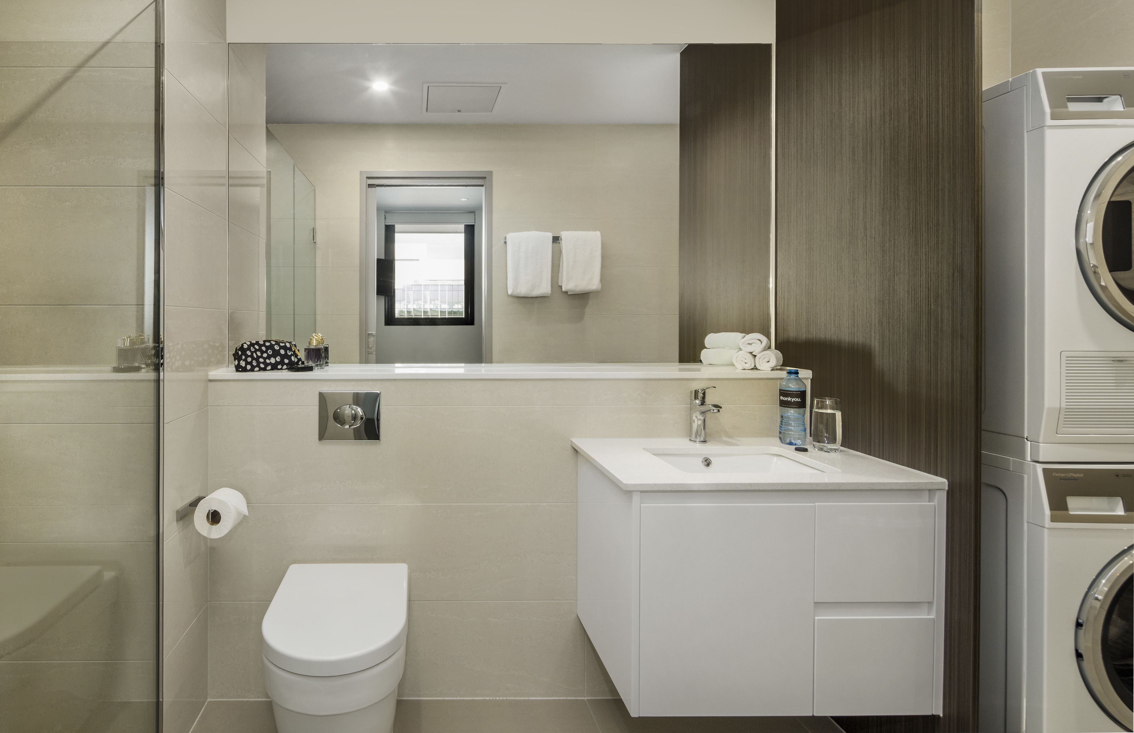 A modern bathroom with a toilet, sink, and washing machine.