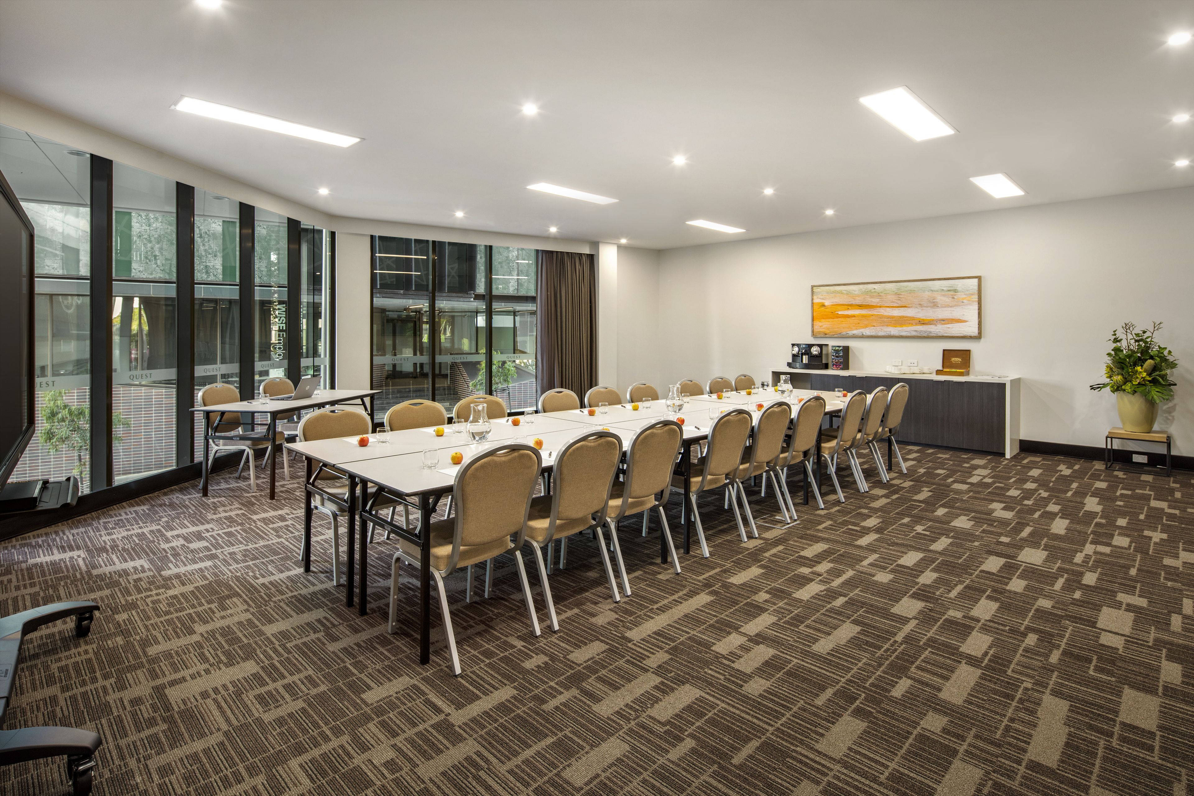 Un salón de conferencias con una mesa larga, sillas y una pequeña cocina.