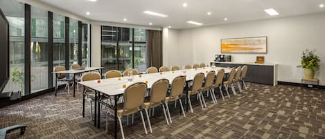 A conference room with a long table, chairs, and a small kitchenette.