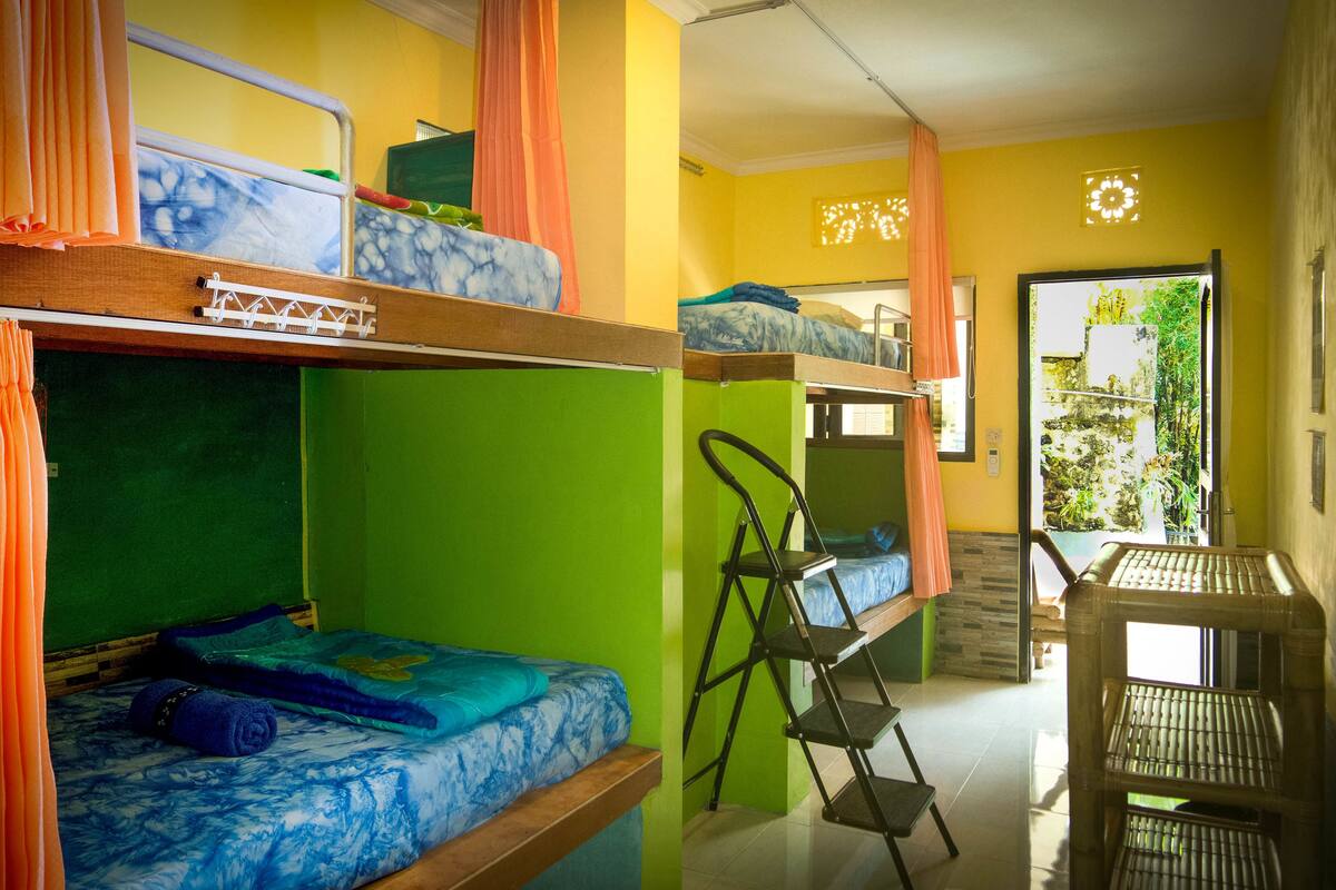 Un dormitorio con literas, una escalera y una ventana con cortinas.