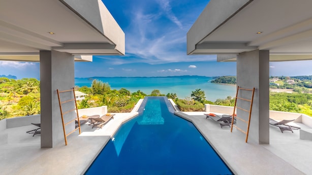 Una piscina infinita moderna con vistas claras al océano y un paisaje tropical.