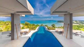 A modern infinity pool with a clear view of the ocean and a tropical landscape. - Villa Leelawadee (Pa Klok)
