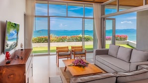 Una sala de estar moderna con un amplio ventanal corredera que da a un balcón con vistas al mar y a las montañas.