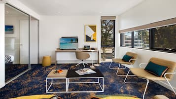 A modern living room with a large TV, a desk, and comfortable seating.