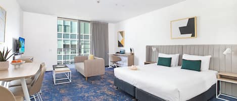 Una habitación de hotel con una cama grande, un escritorio, una silla, un sofá y una mesa de comedor.