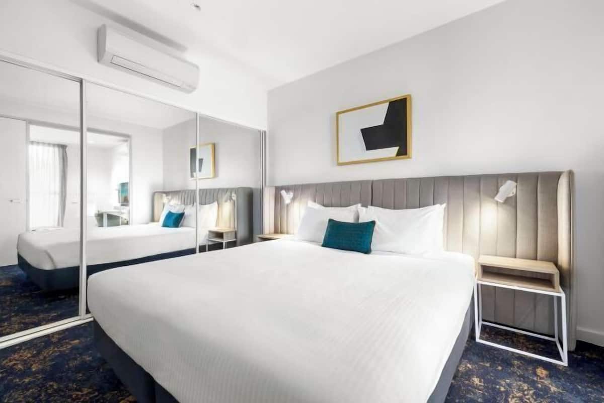 Una habitación de hotel con una cama grande, una mesita de noche, un espejo y una obra de arte colgada en la pared.