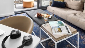 Un salón moderno con un sofá, un reposapiés y una mesa de centro con una revista y una copa de vino.
