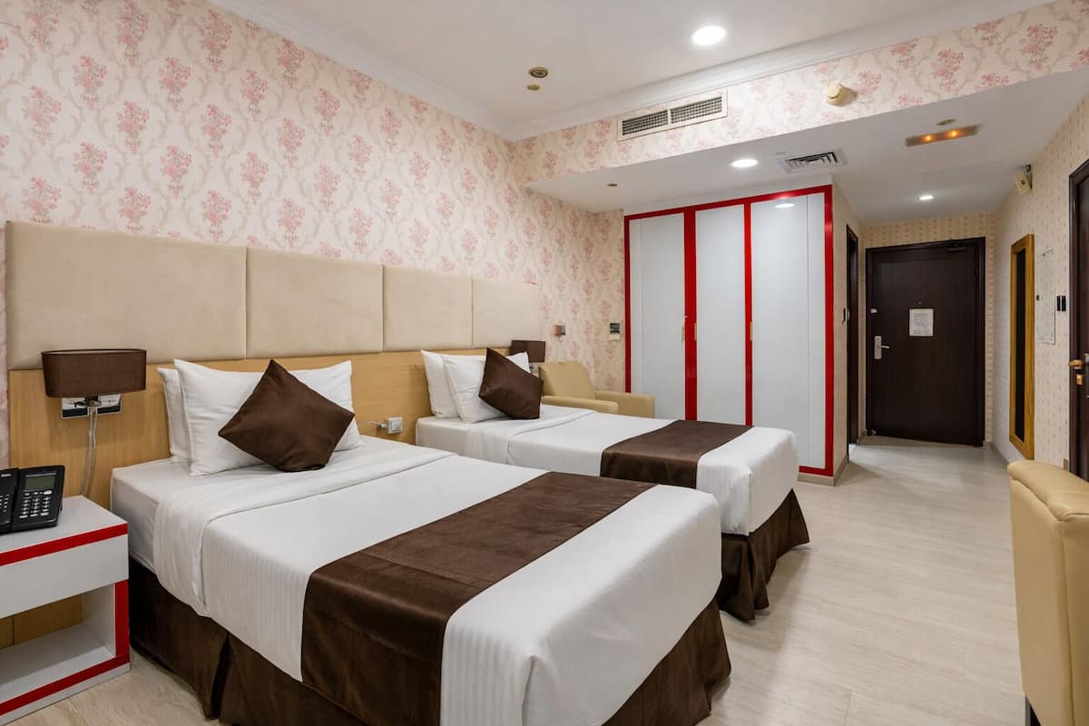 A hotel room with two beds, a bedside table with a phone, and a wardrobe with a red accent.