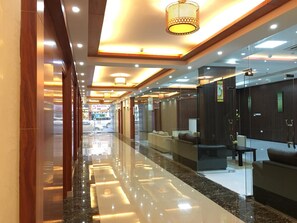 A modern hotel lobby with a reflective marble floor, glass partitions, and a seating area with sofas. -  Royal Tulip Hotel, Dubai (Dubai)