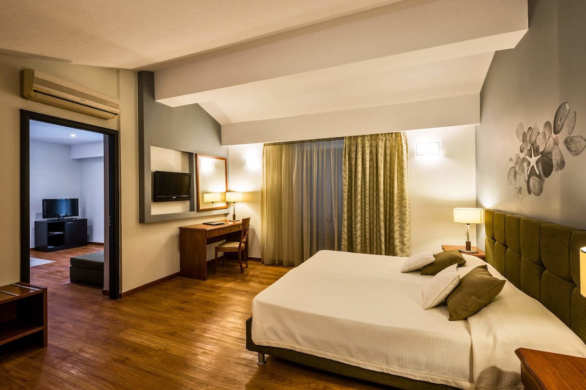 A hotel room with a bed, desk, chair, and a television.