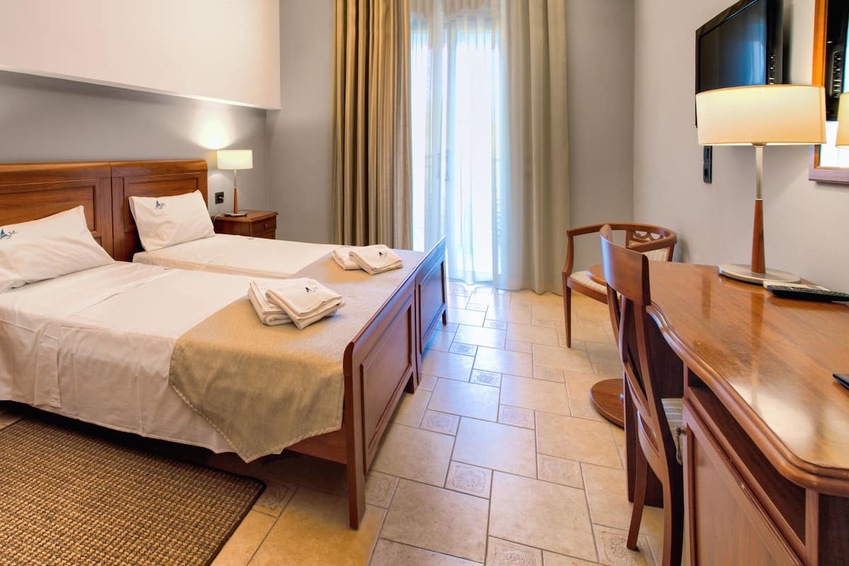 A hotel room with two beds, a desk with a computer, a TV, and a bathroom.
