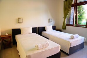 A hotel room with two beds, a window with curtains, and decorative wall mirrors.