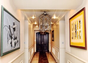 A hallway with a chandelier, framed artwork, and a dark wooden door. - Westfoster Harbour Boutique Residences (Lagos)