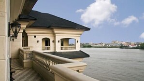 Un edificio con balcón que da a un río, con piso a cuadros y barandilla.