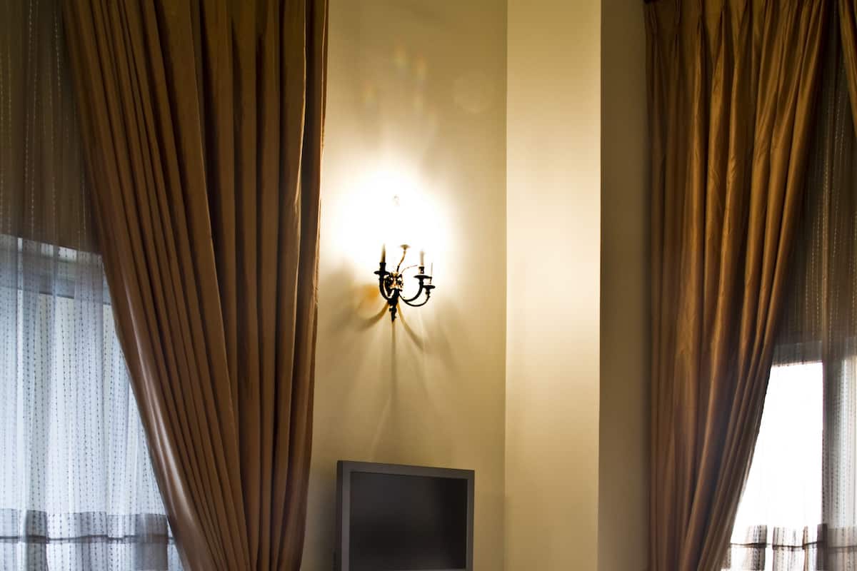 A hotel room with a large bed, a flat-screen TV mounted on the wall, and a bedside table with a remote control.