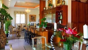 Uma sala de jantar com uma mesa de vidro, cadeiras e um armário de madeira com objetos decorativos.