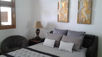 A bedroom with a bed, a nightstand, a lamp, and two wall art pieces.