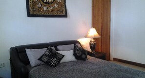 Une chambre à coucher avec un lit, une table de chevet avec une lampe et une œuvre d’art accrochée au mur.