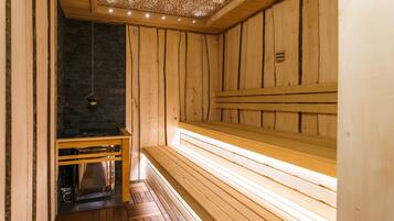 A sauna with wooden benches and a stone wall.
