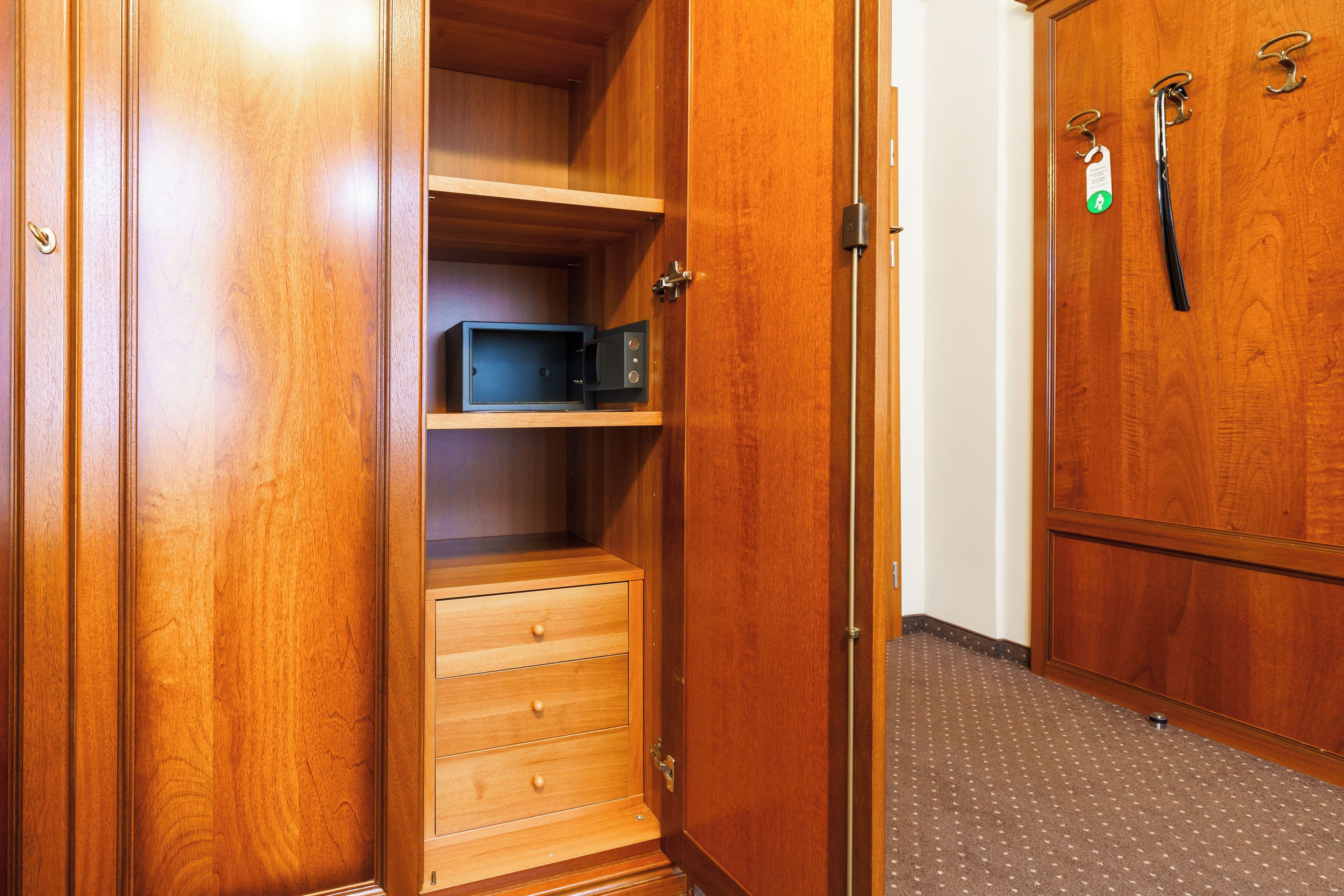 A wooden wardrobe with a microwave and a small drawer.