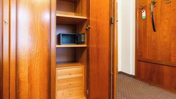 A wooden wardrobe with a microwave and a small drawer.