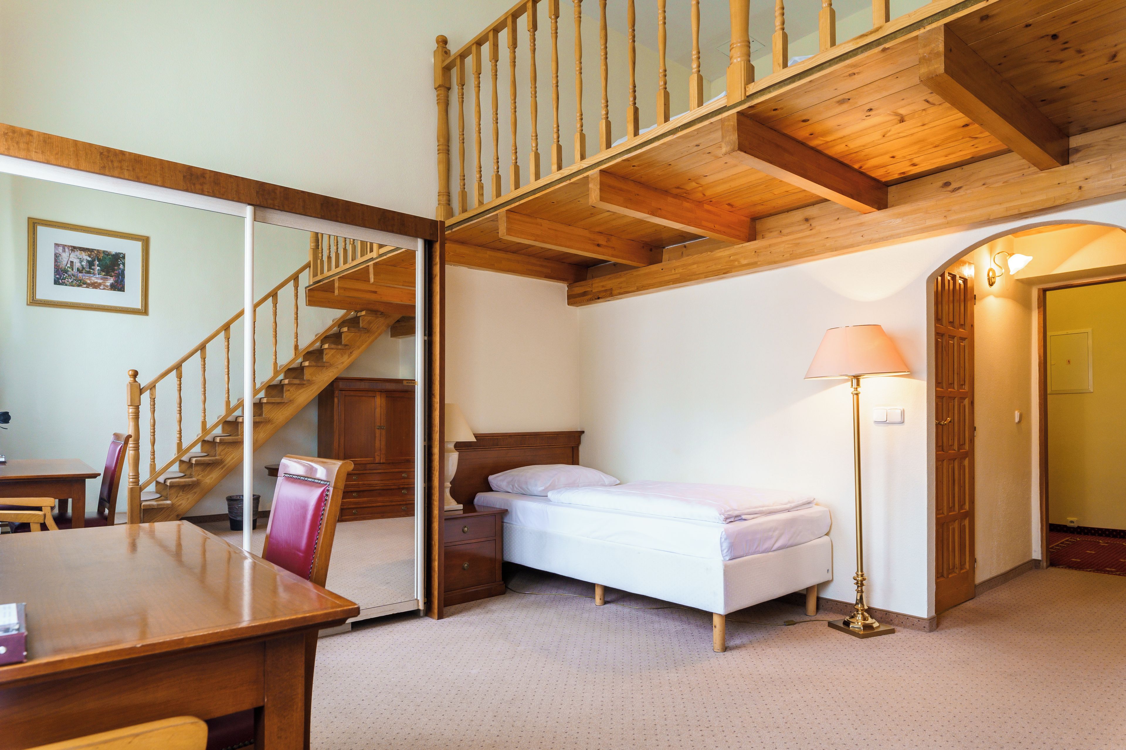 Une chambre avec un escalier en bois, un lit, une table de chevet et un bureau avec une chaise.