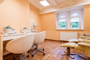 A dental clinic with a wooden floor, white chairs, and a window with blinds.