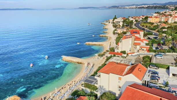 A coastal town with a beach, clear blue waters, and buildings with red roofs. - Pansion Martin (Podstrana)