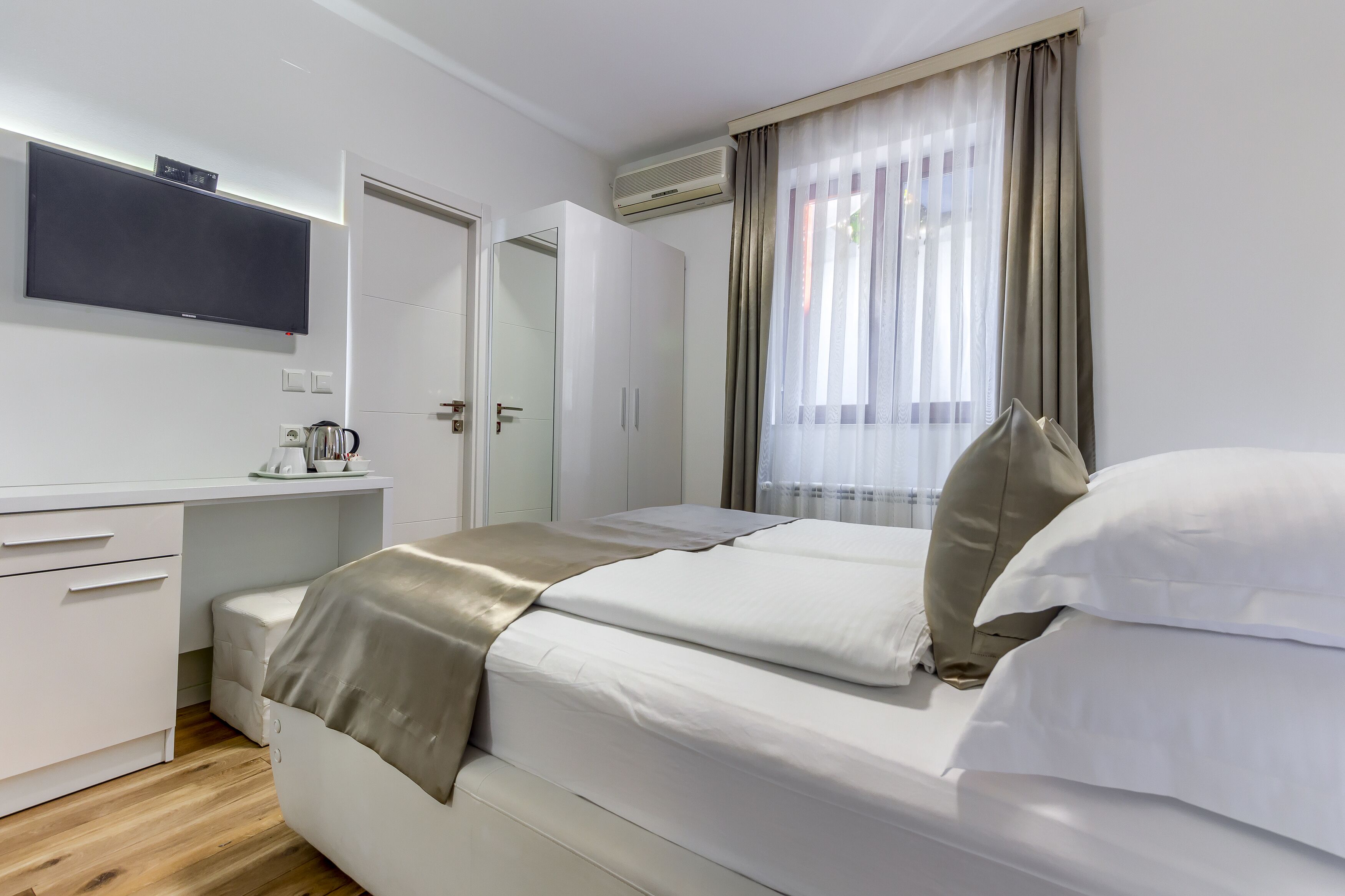 Ein modernes Schlafzimmer mit Bett, Schreibtisch, Fernseher und Kleiderschrank.