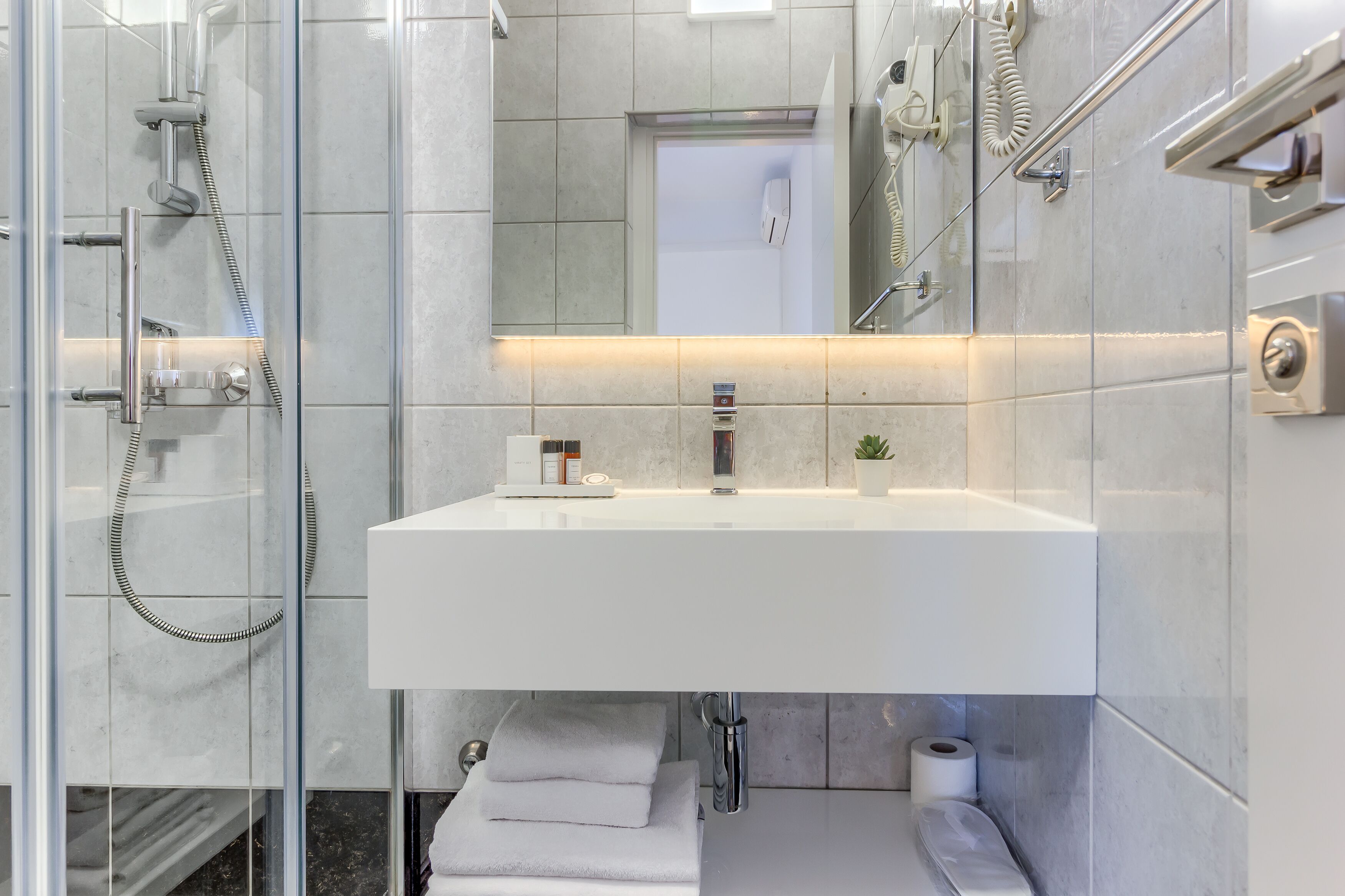 A modern bathroom with a glass-enclosed shower, a white sink, and a mirror above it.