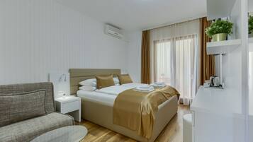 Et moderne hotelværelse med en seng, en sofa, et lille bord og et tekøkken.