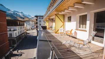 Une terrasse en bois avec des sièges extérieurs et une vue sur des montagnes enneigées.